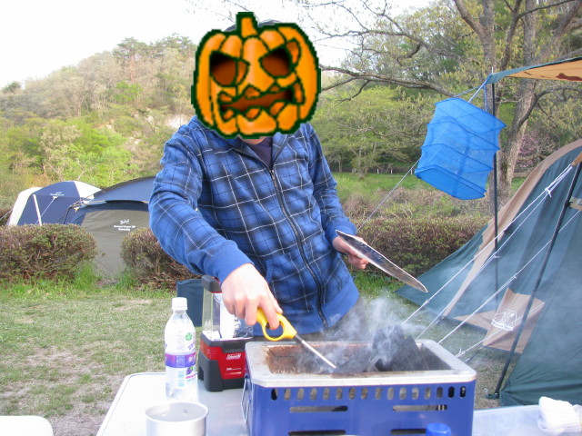 バーベキューコンロの炭に火を着ける息子