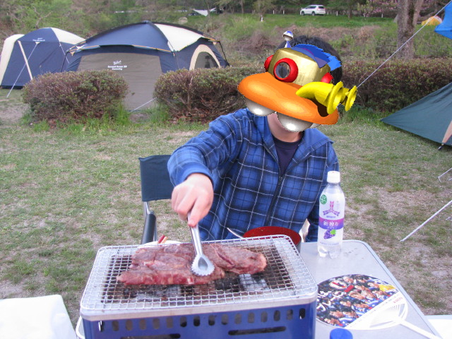 肉を焼きながらカレーライスを食べる息子