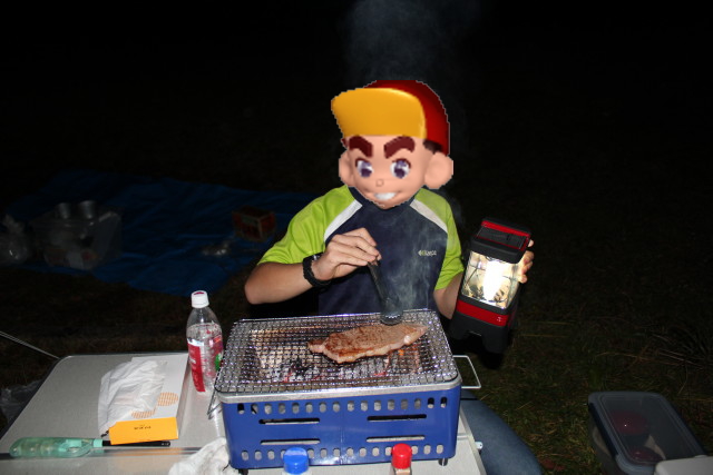 バーベキューコンロでステーキを焼く息子