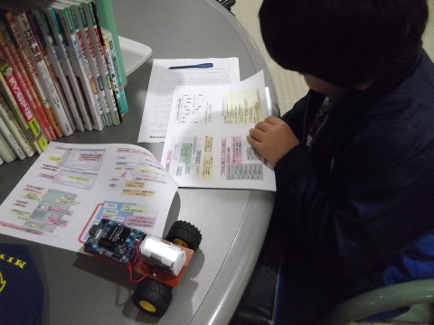 ロボット教室の資料を見る息子