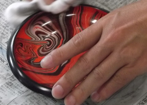 塗料が付いた器を職人さんが処理