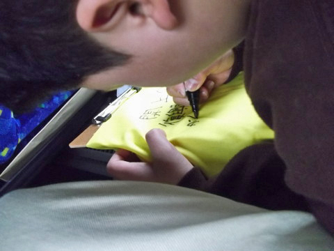 被災地区へ送る黄色いハンカチにメッセージを書く息子