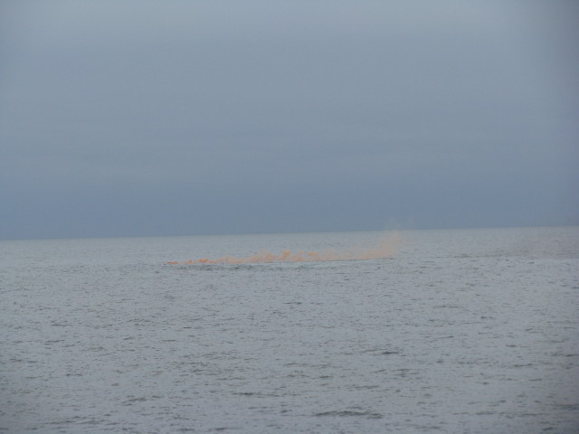 海中に落ちた人の場所から発煙筒が炊かれている